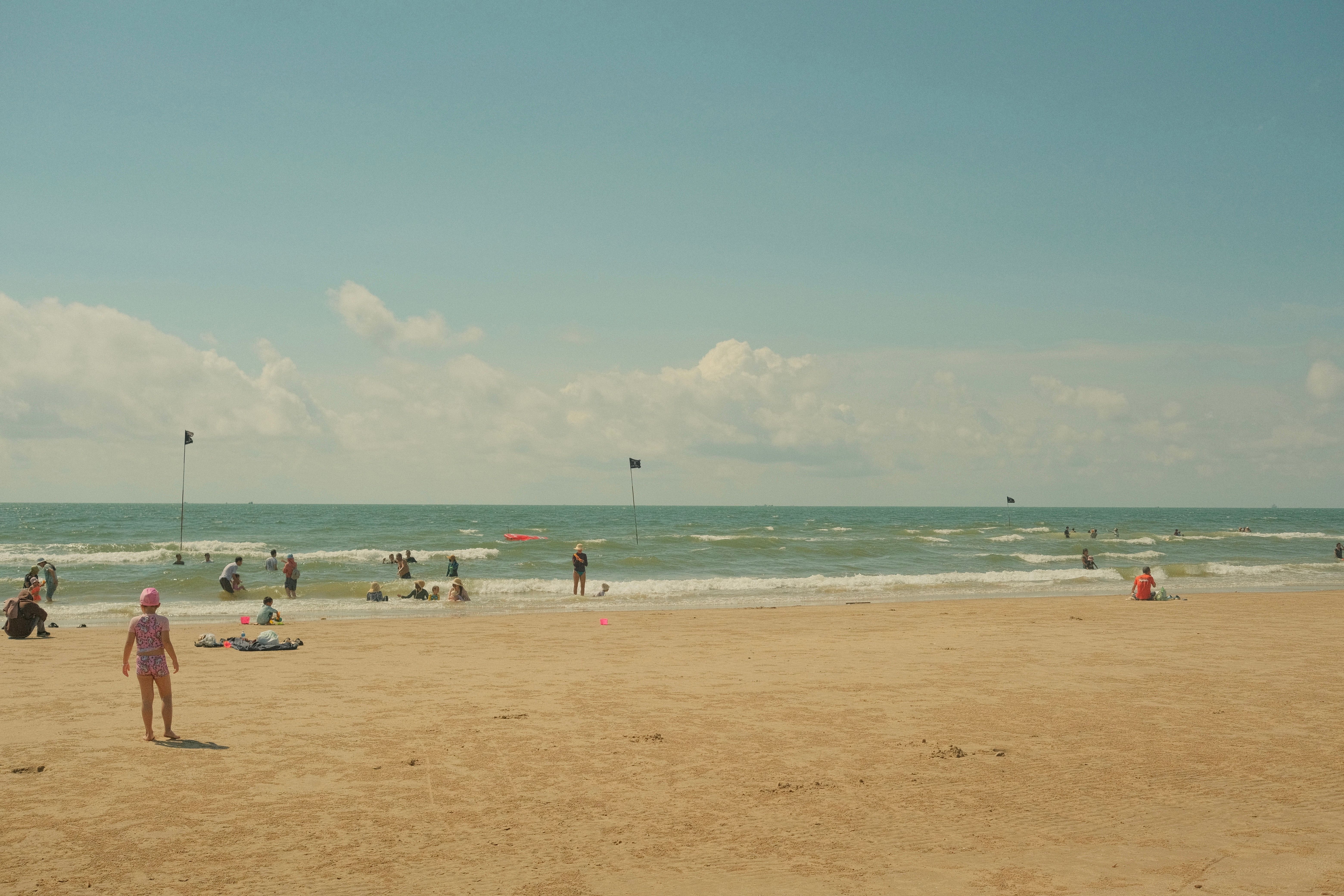 Sunny Beach Day with People Enjoying the Sea · Free Stock Photo