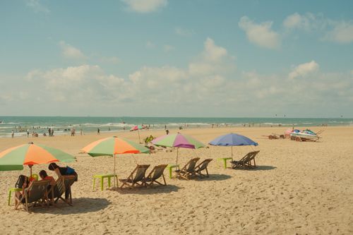 Free Scenic beach with colorful umbrellas, chairs, and people enjoying a sunny day. Stock Photo