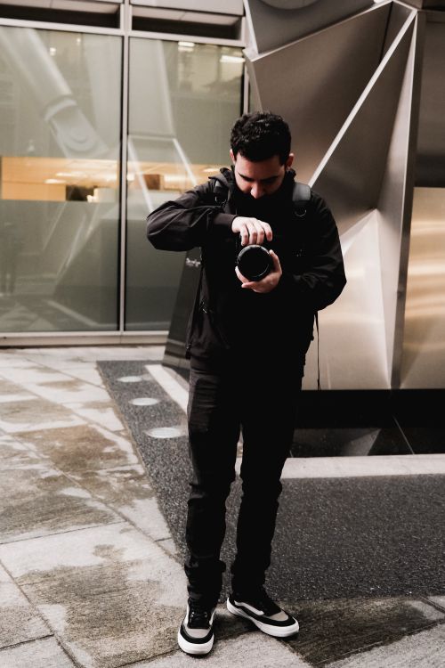 Free A young male photographer taking a shot in an urban setting with modern architecture. Stock Photo