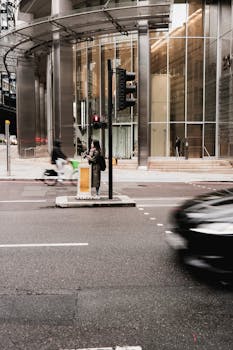 Dynamic urban street scene showcasing motion blur of vehicles and pedestrian in a modern city setting.