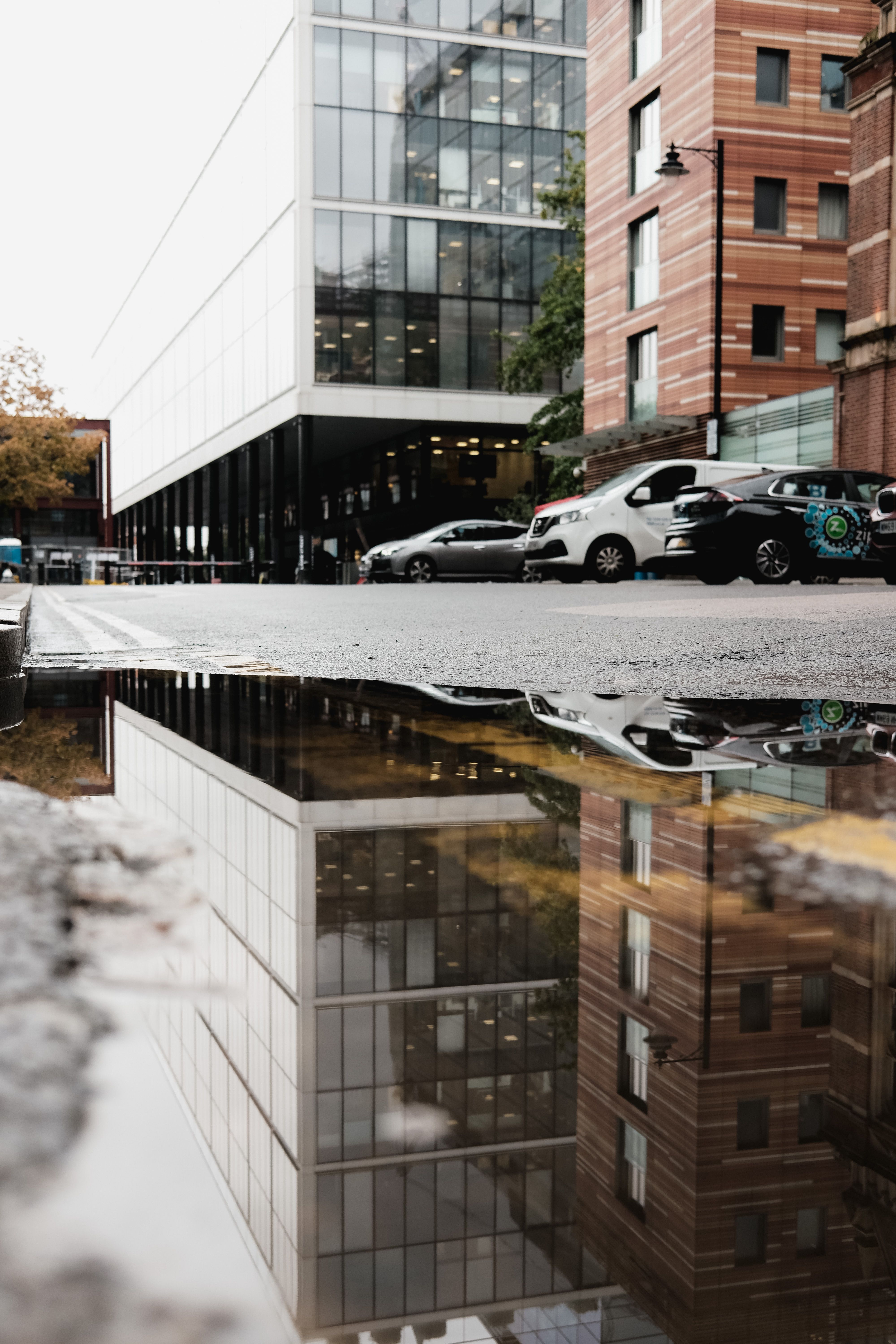 Urban building reflection in rainy puddle · Free Stock Photo