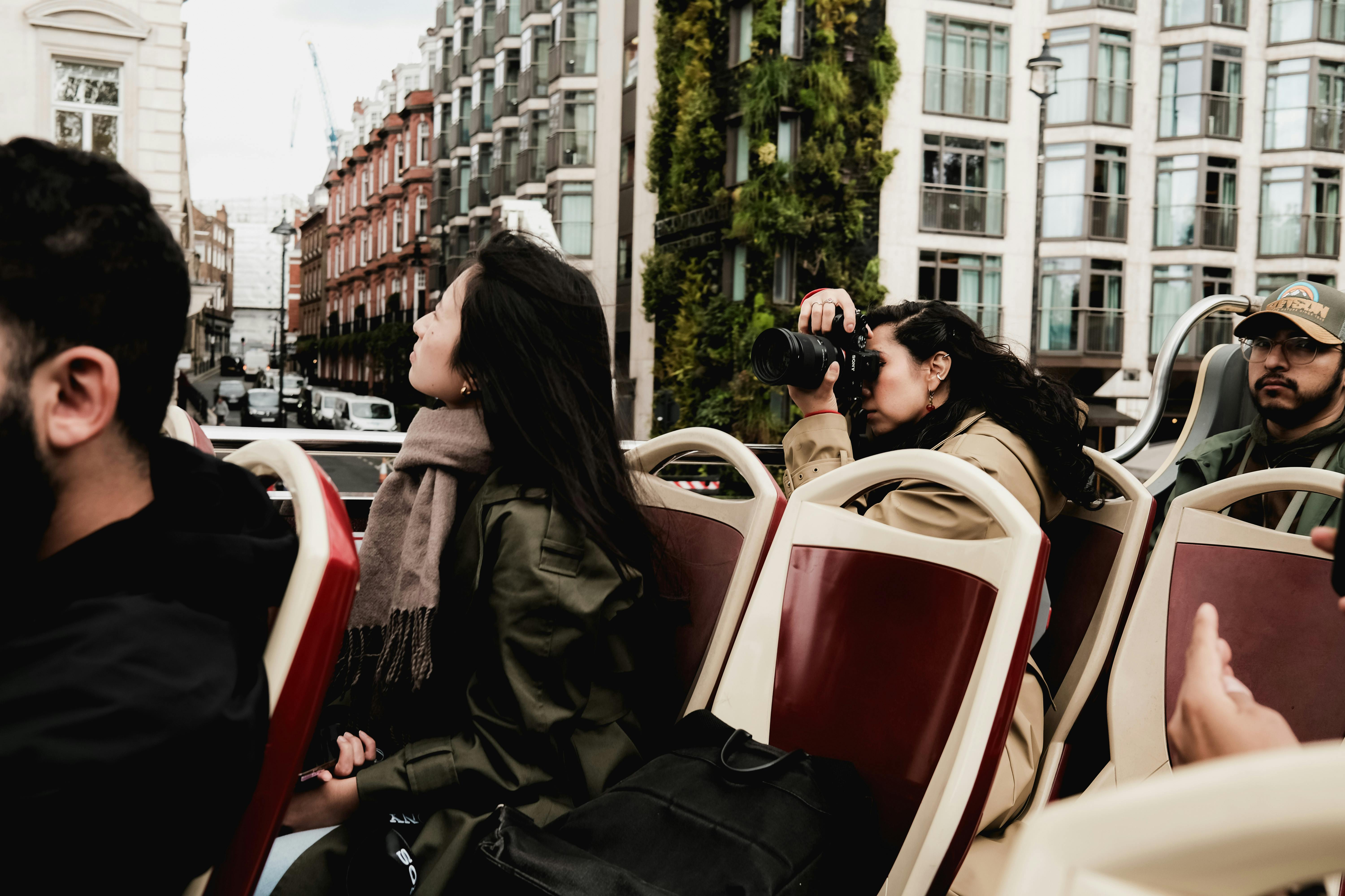 Group of adults enjoying a city tour on an open-top bus, capturing memories.