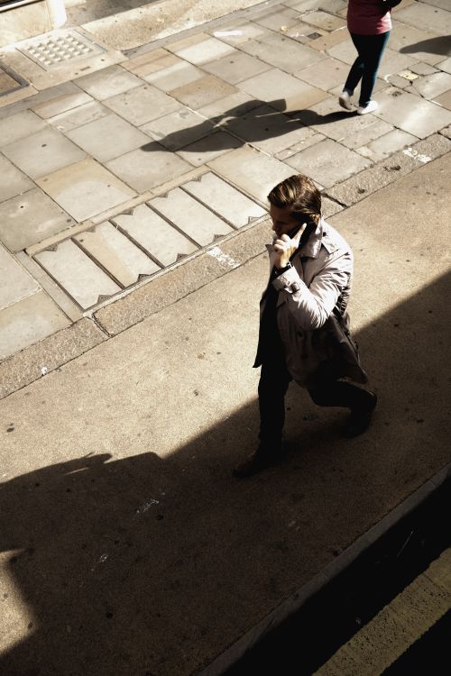 Free A man walks on a city street, engaged in a phone call during the day. Stock Photo