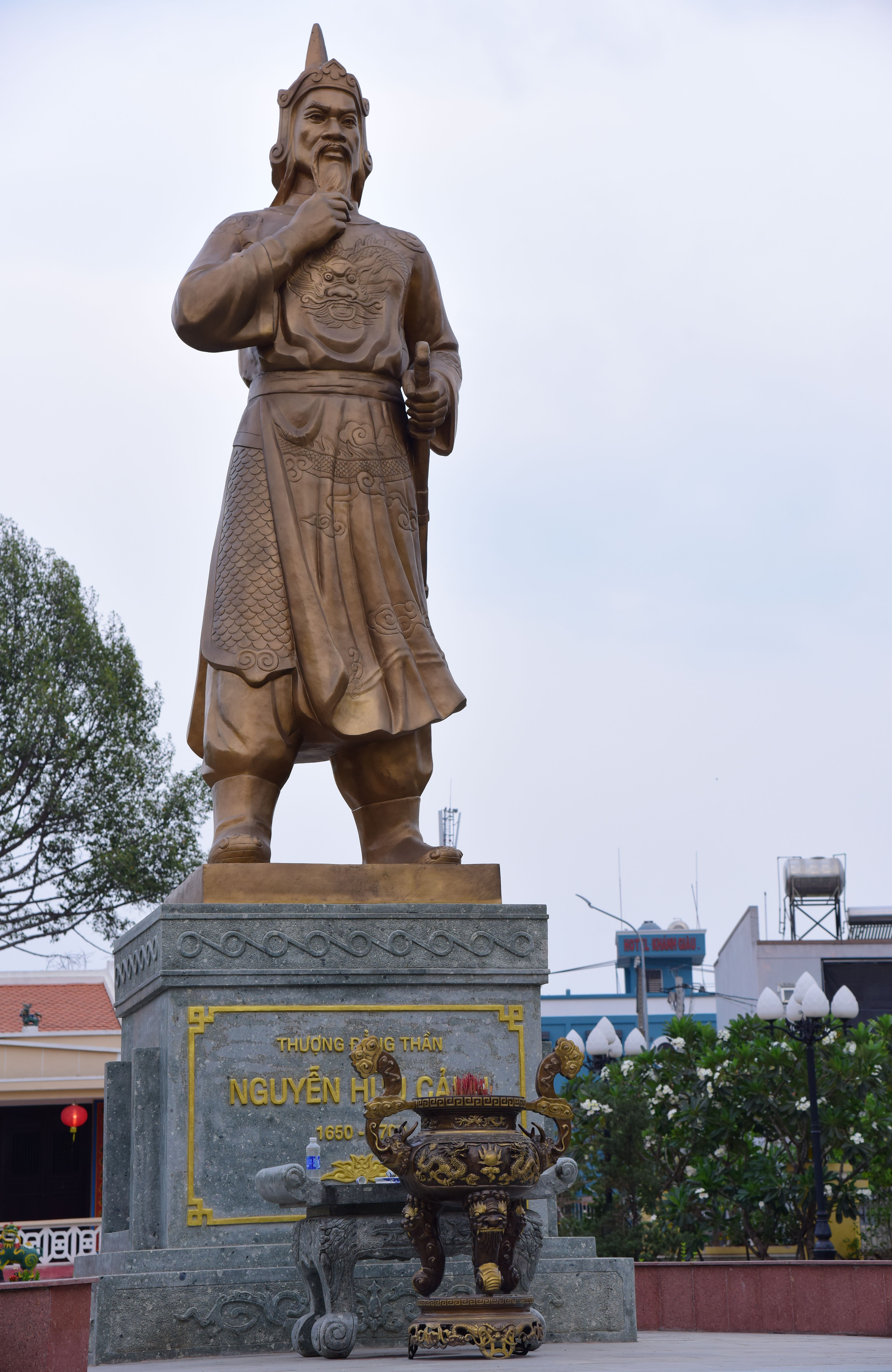 Statue of a historical figure in a Vietnamese urban environment.