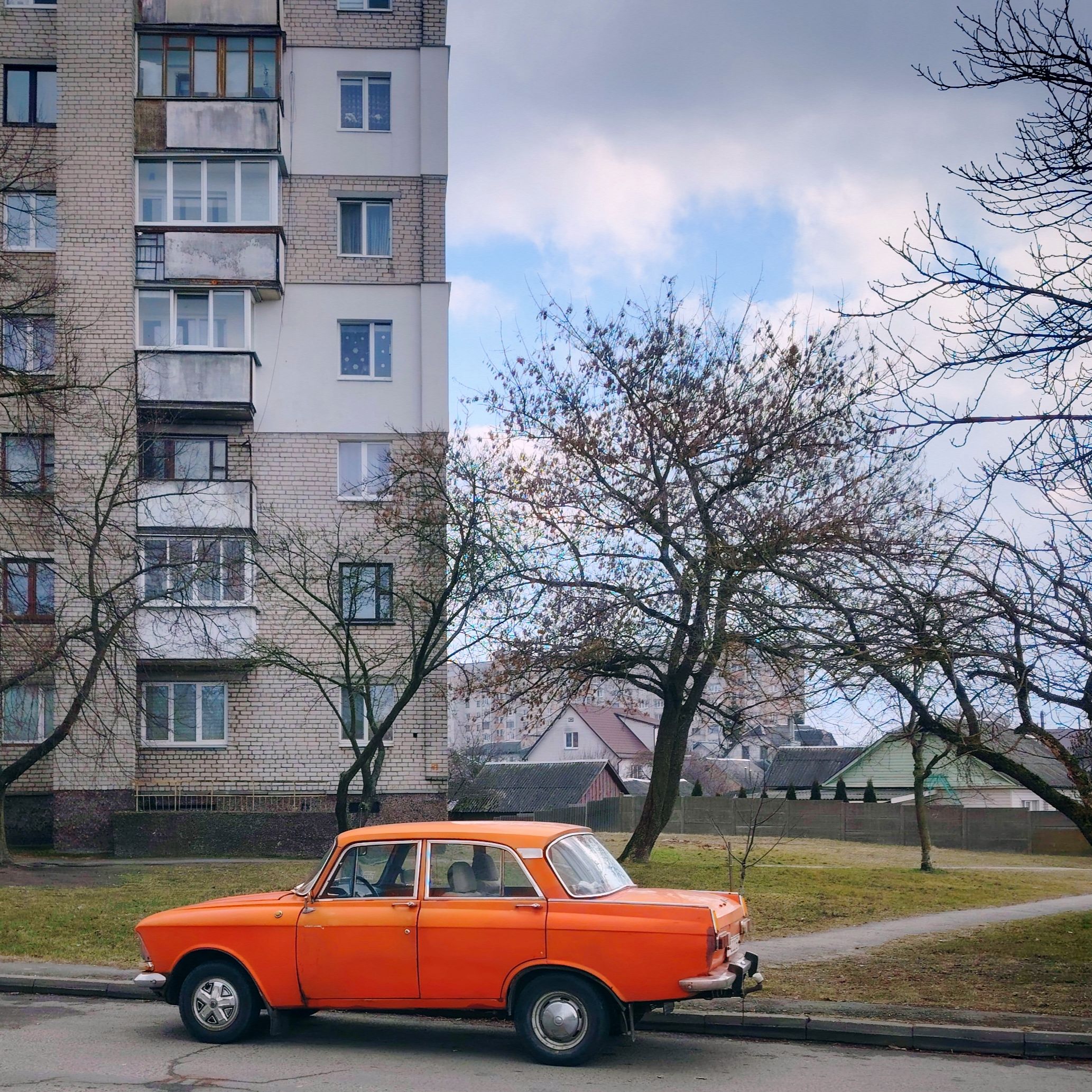 Vintage Orange Car Parked Near Residential Building · meta.free_stock.photo