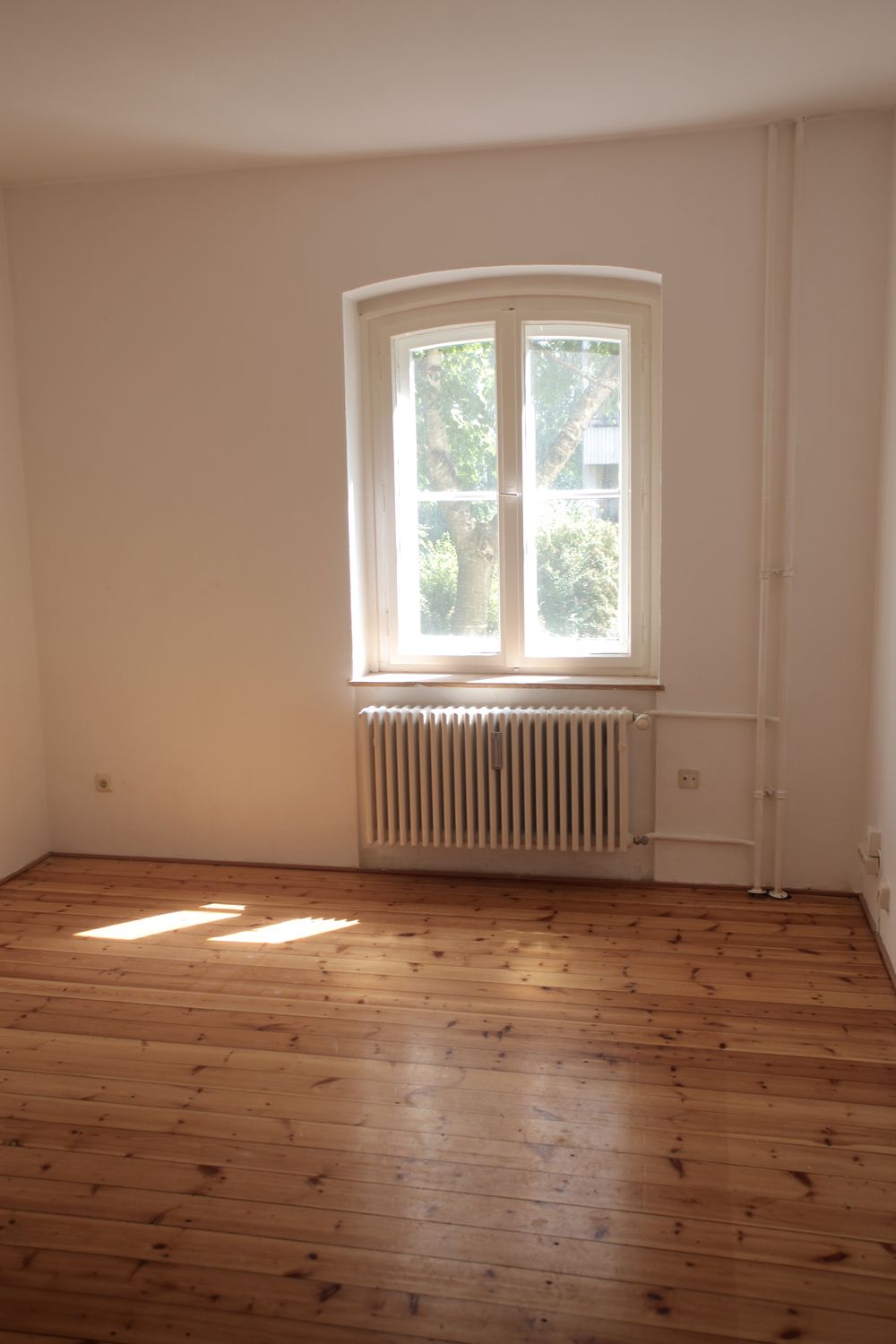 Pièce claire vidée, parquet et grande fenêtre, avant remise en état
