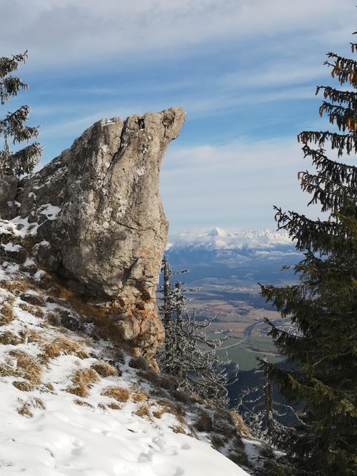 Free A rugged rocky outcrop set against a vast snowy valley with distant mountains. Stock Photo