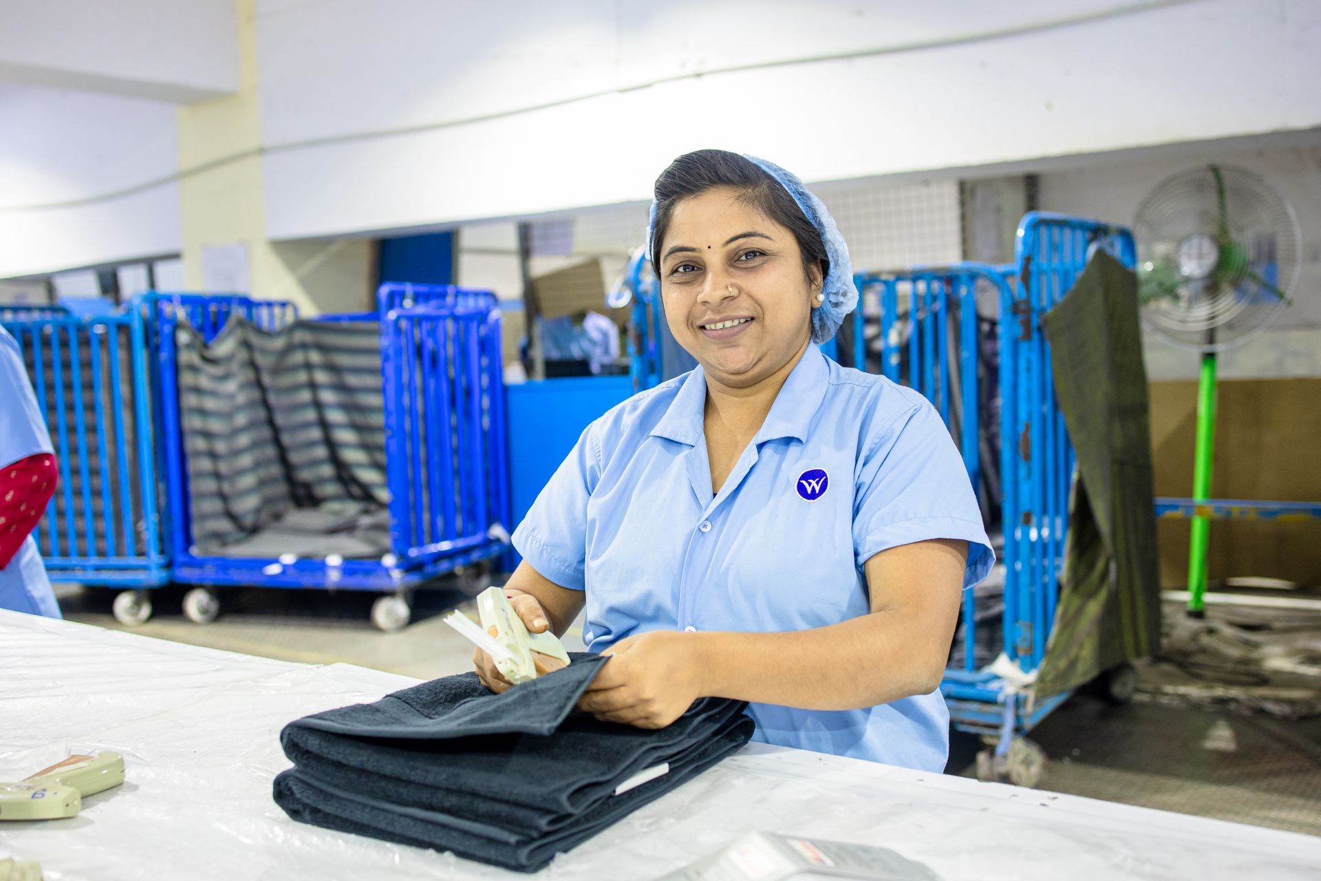 Female textile worker folding clothes in an industrial factory environment.