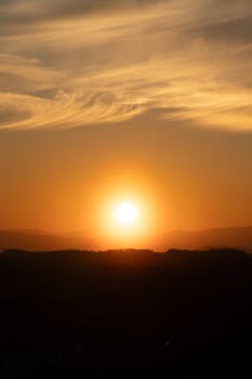 A tranquil sunset scene with golden hues and silhouetted mountains creating a peaceful ambiance.
