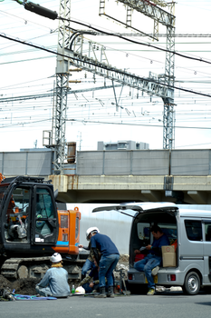Workers in Osaka, Japan at a construction site near train tracks and power lines.