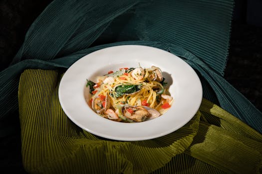 Delicious seafood pasta with shrimp, clams, and vegetables, artfully presented in a white dish.