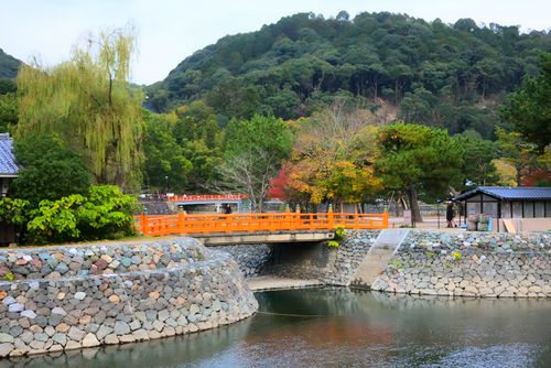 Free Colorful Japanese landscape with a vibrant orange bridge and lush autumn foliage. Stock Photo