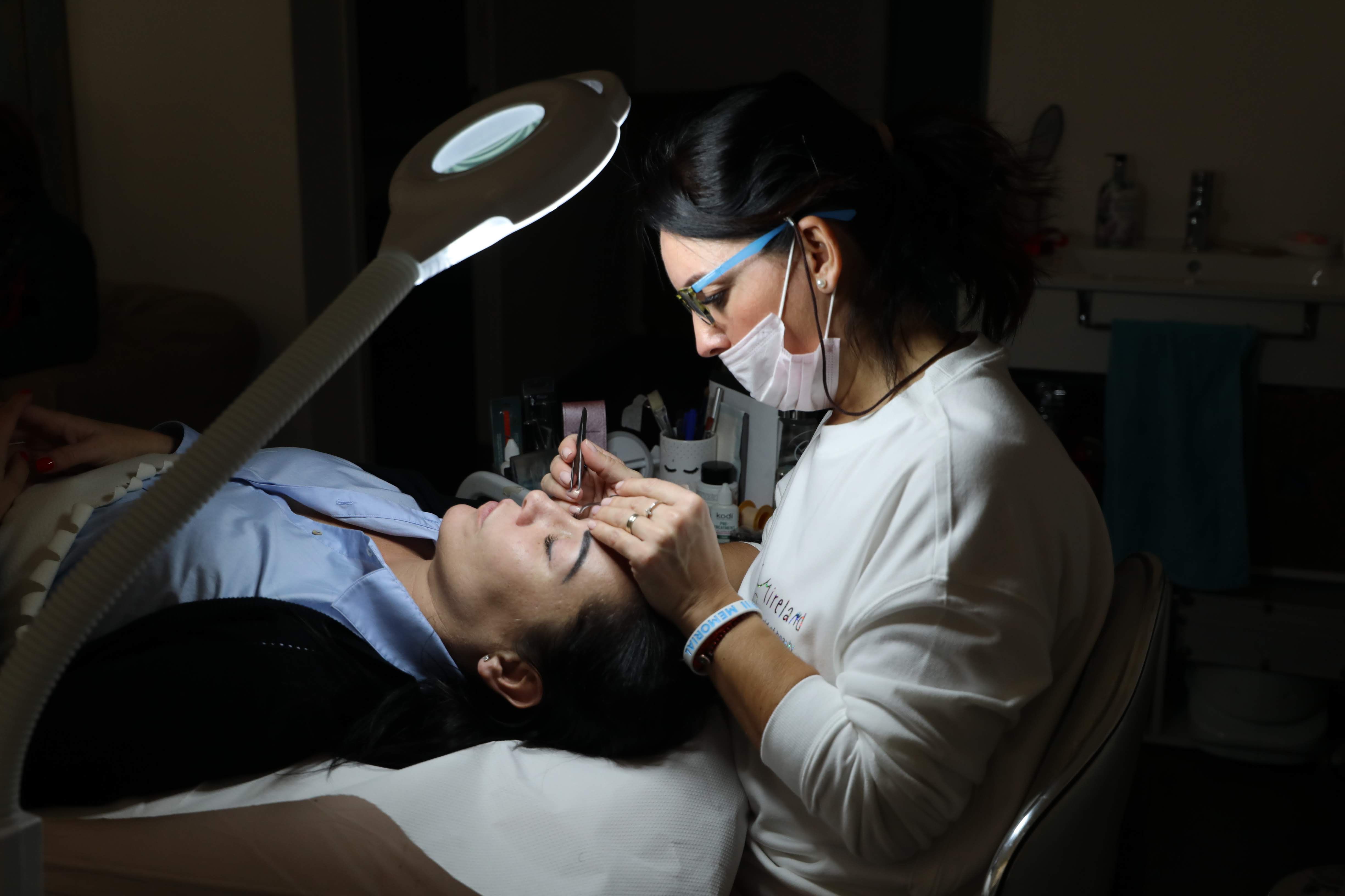gratis Een schoonheidsspecialist verzorgt de wenkbrauwen van een klant professioneel in een salon, onder gericht licht. Stockfoto