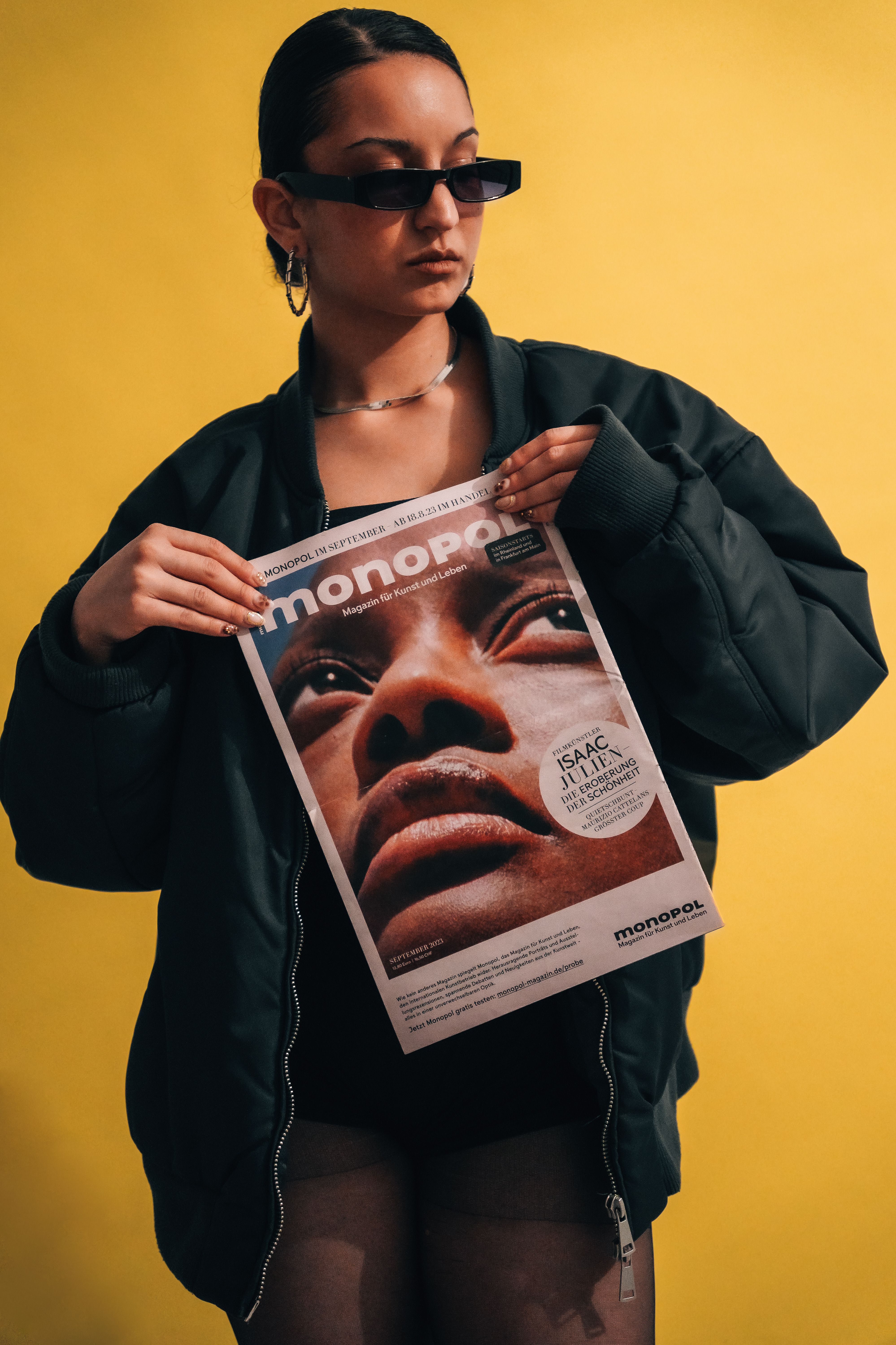 Trendy woman holding fashion magazine with bold cover in studio