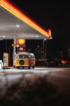 Retro van parked at illuminated gas station under the night sky.