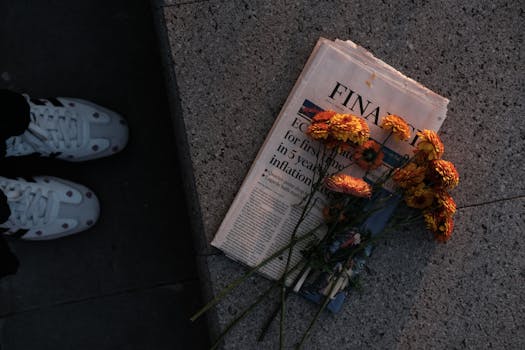 Yellow daisies placed on a financial newspaper on stone pavement during sunset.