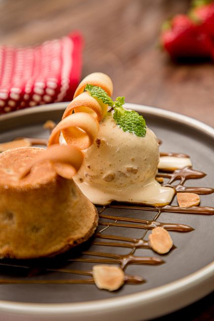 A metal loaf pan of creamy no-churn vanilla ice cream with a scoop lifted out, showing a smooth, dense texture flecked with vanilla bean.