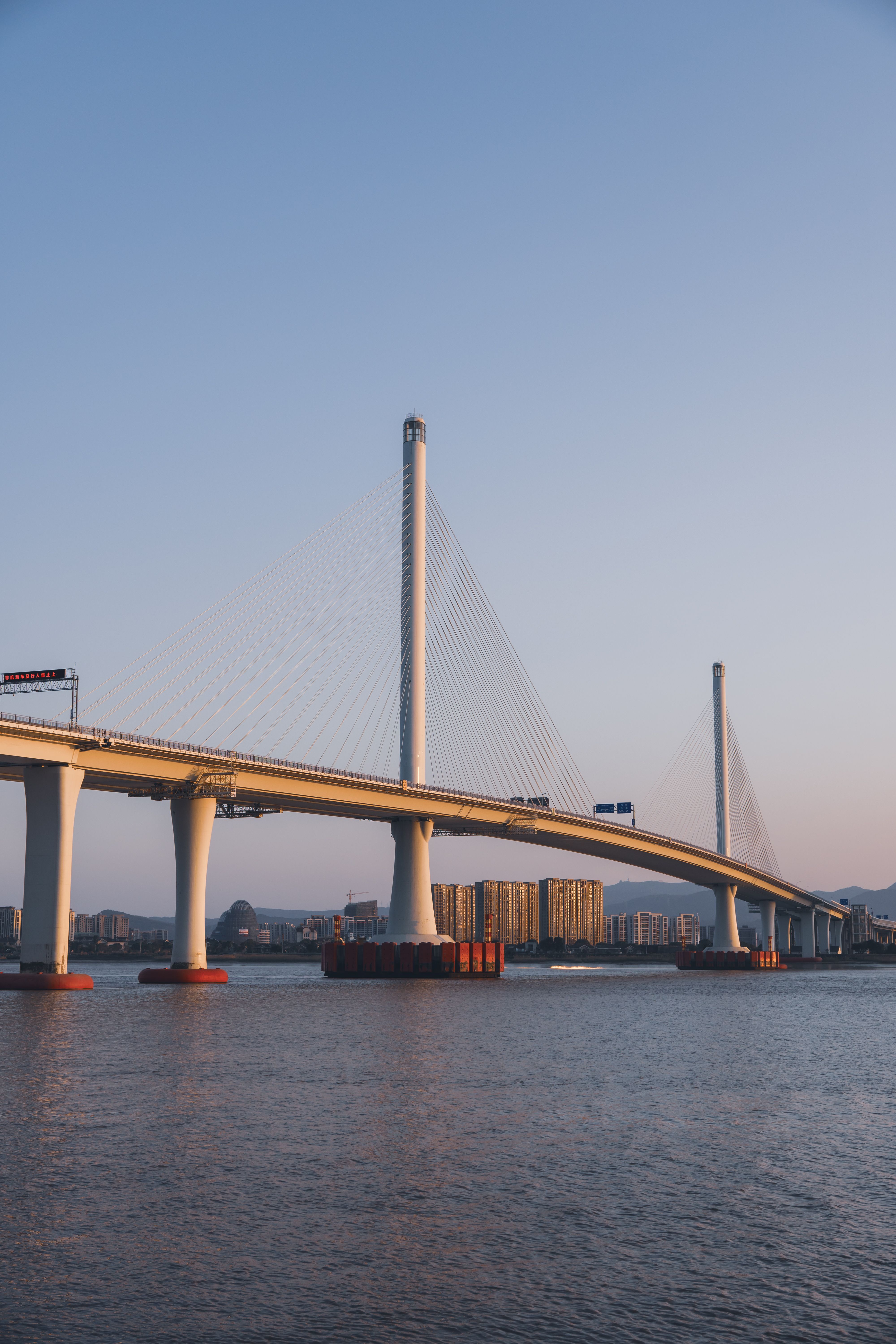 Modern Cable-Stayed Bridge Over Calm River at Sunset · Free Stock Photo