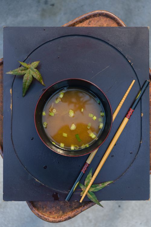 Free A bowl of miso soup with scallions, paired with chopsticks and decorative leaves. Stock Photo