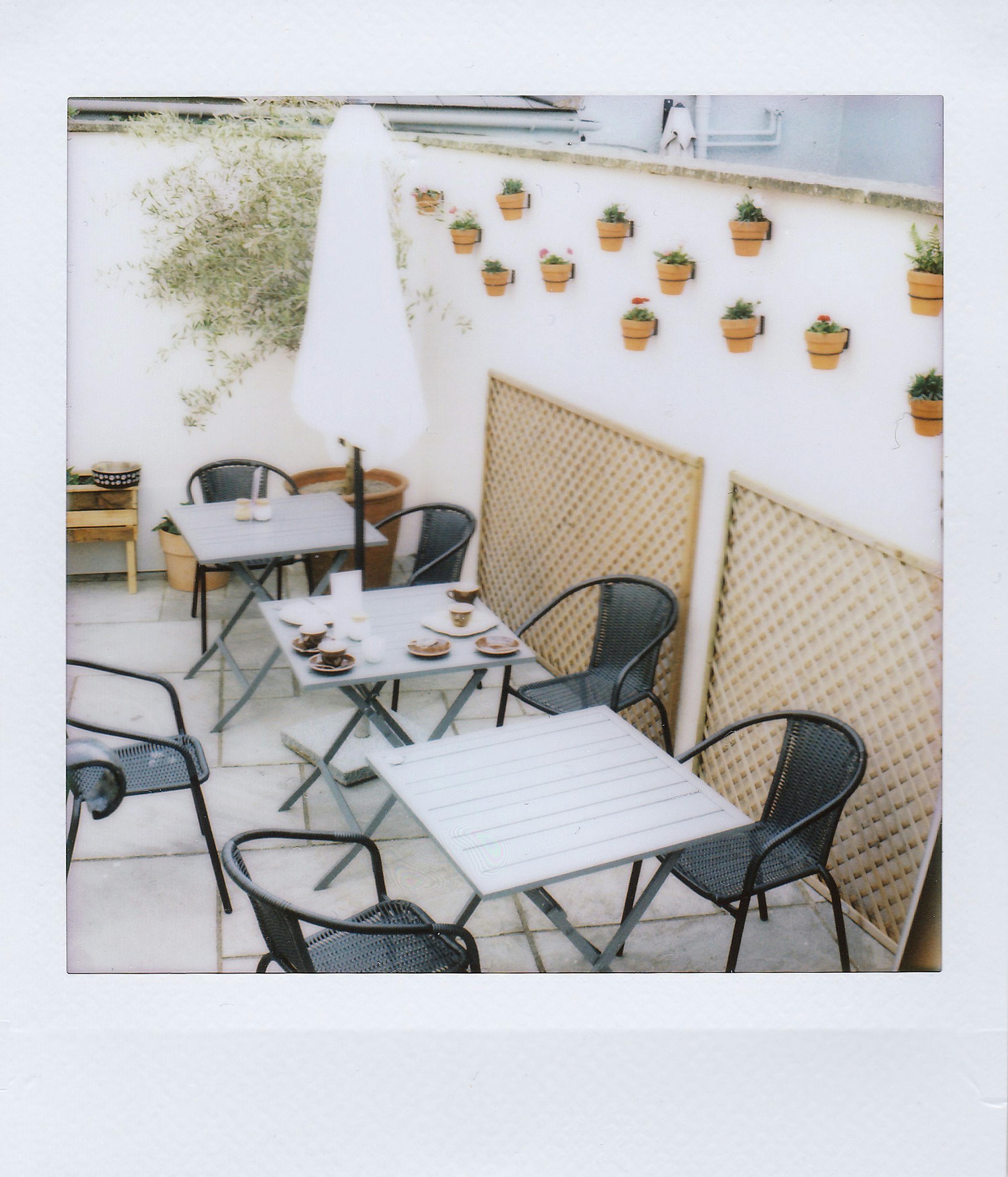 A charming outdoor cafe featuring minimalist decor and hanging plants.