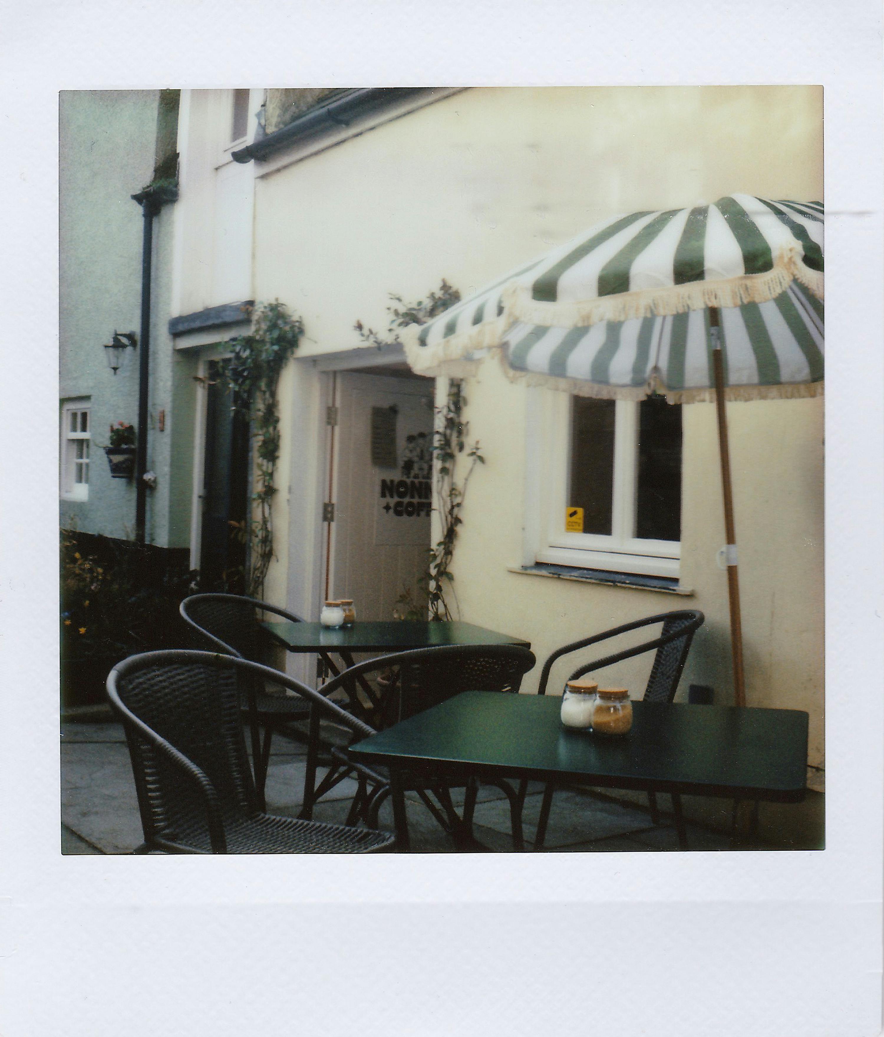 A quaint outdoor café setting with wicker chairs and a striped umbrella.