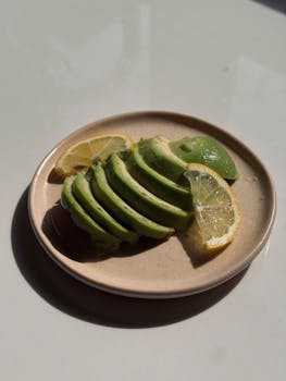Freshly sliced avocado with lemon slices on a minimalist ceramic plate.