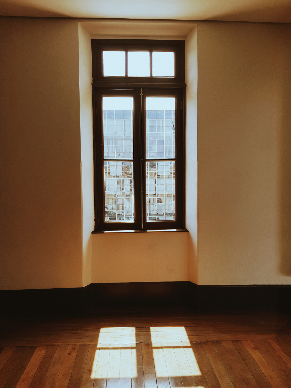 Sunlight streaming through windows casting geometric shadows on hardwood floor
