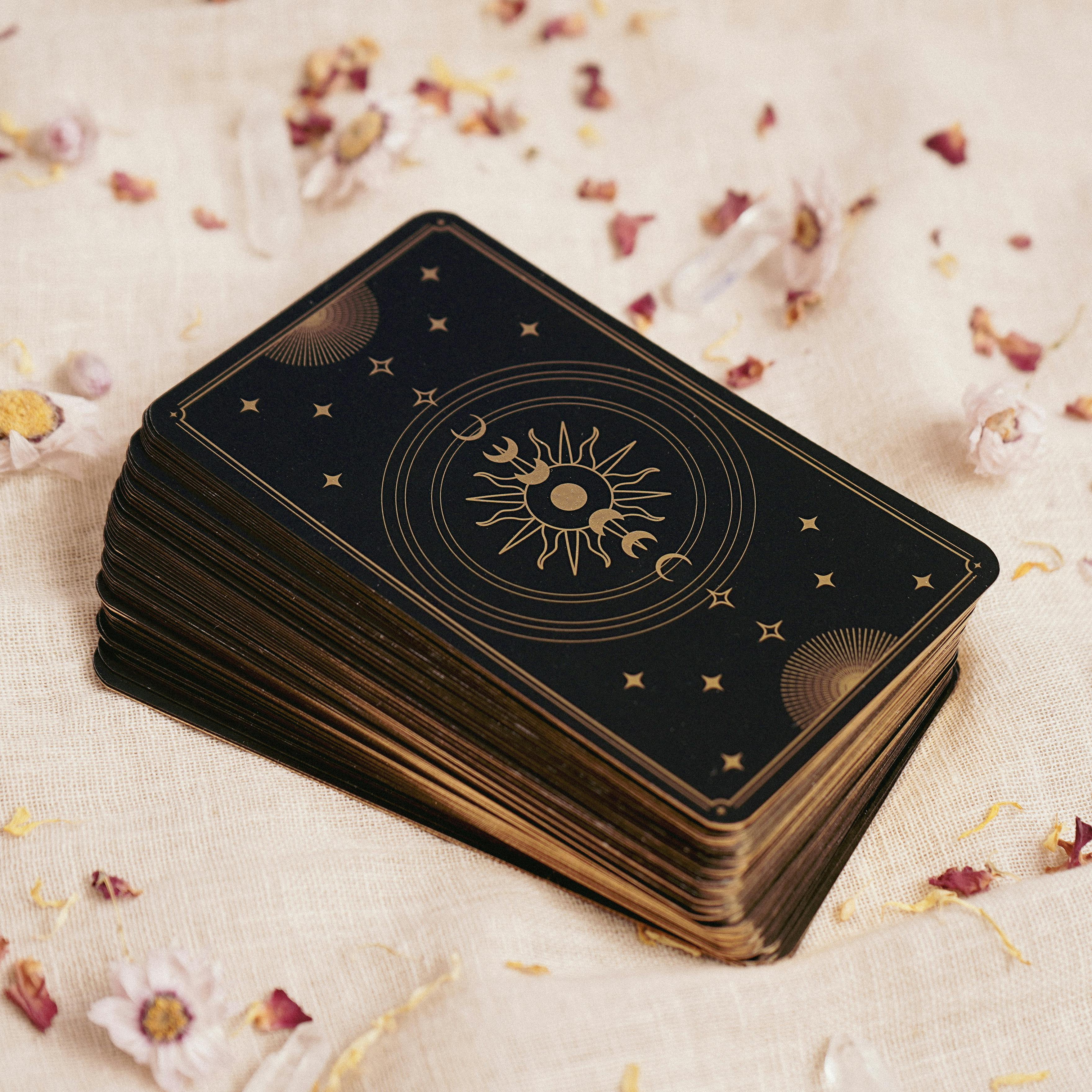A stacked deck of tarot cards with celestial design on a beige fabric background.