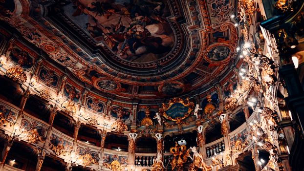 Ornate Baroque theater interior showcasing intricate frescoes and lavish architectural details.
