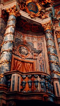 A detailed view of an ornate Baroque church interior with intricate columns and golden embellishments.
