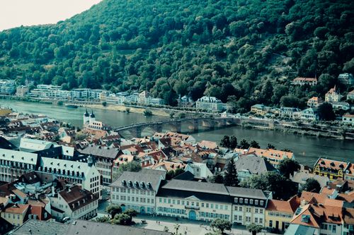 Free A scenic aerial view of a picturesque European town by a river with lush hills in the background. Stock Photo
