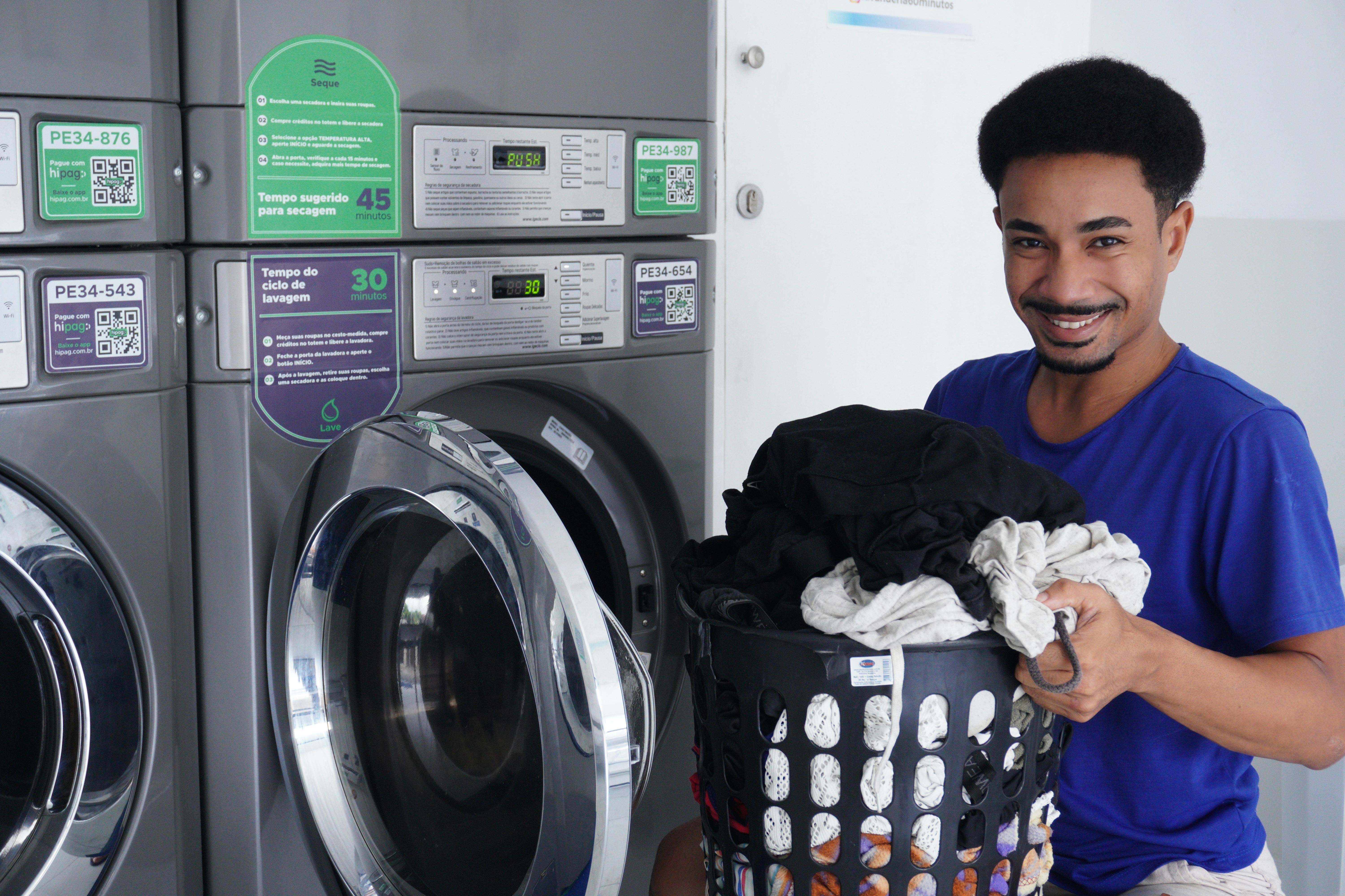 Gratis Hombre sonriente sosteniendo una cesta de ropa en una lavandería, listo para lavar la ropa. Foto de stock