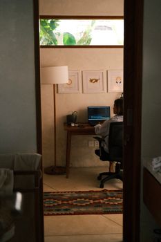 Woman working on a laptop in a cozy home office, perfect for remote work inspiration.