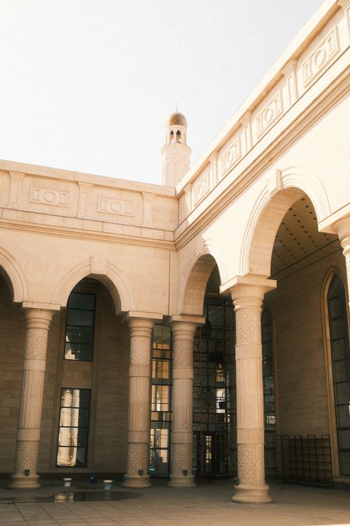 Free Beautiful Islamic architecture featuring arches and a tall minaret under a clear sky. Stock Photo