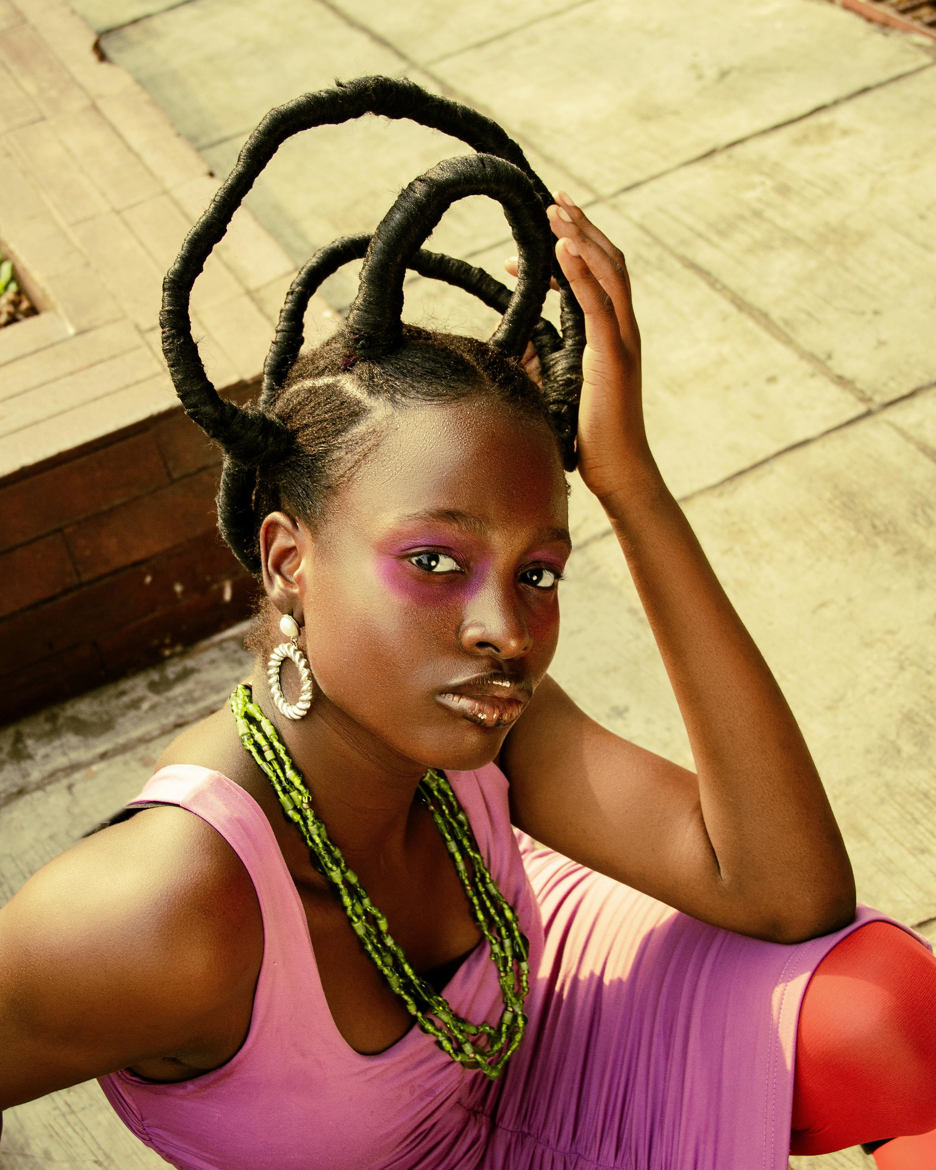 Artistic portrait of a stylish woman with expressive makeup and creative hairstyle outdoors.