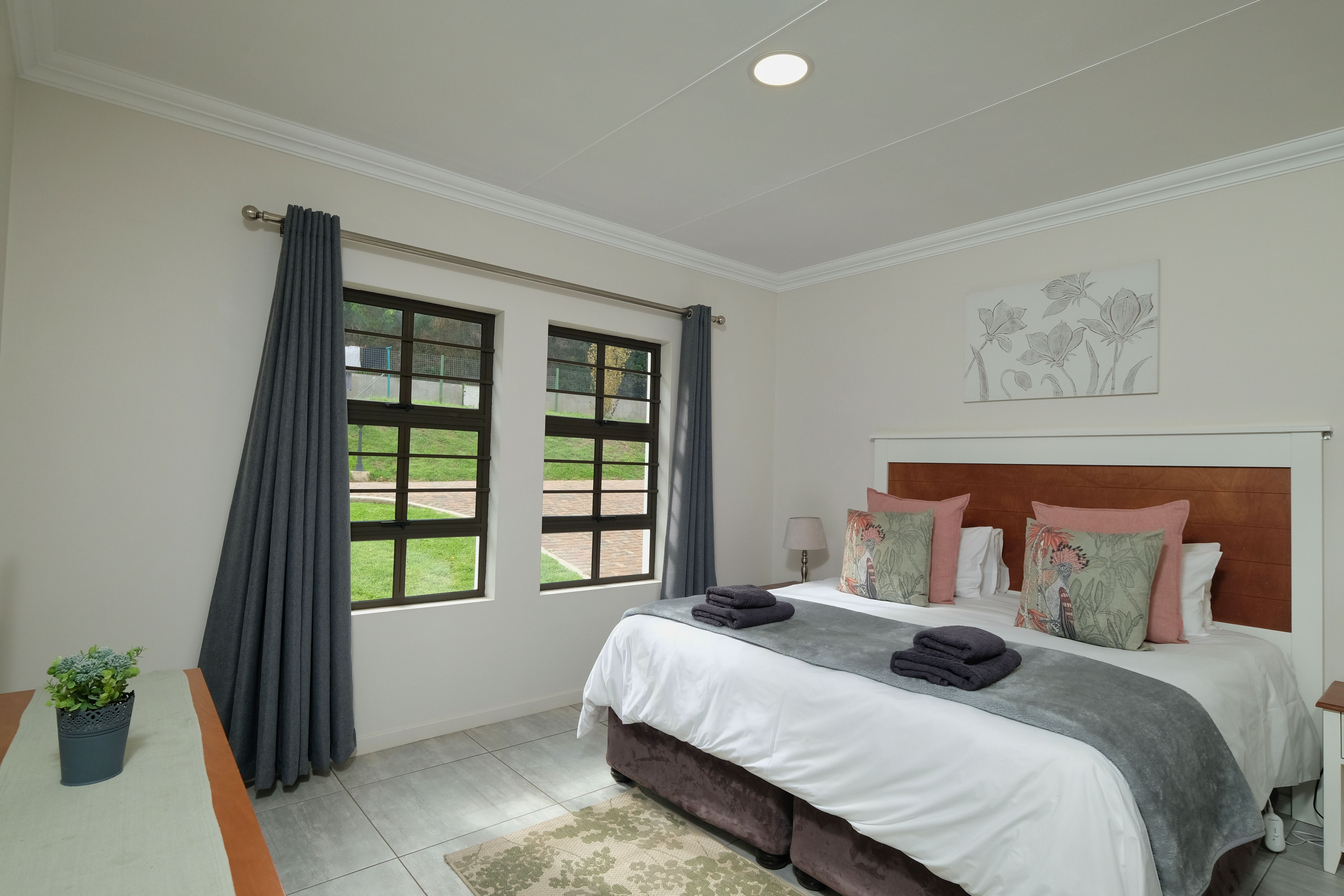 Chambre moderne joliment décorée avec un grand lit, des rideaux élégants et de la lumière naturelle.
