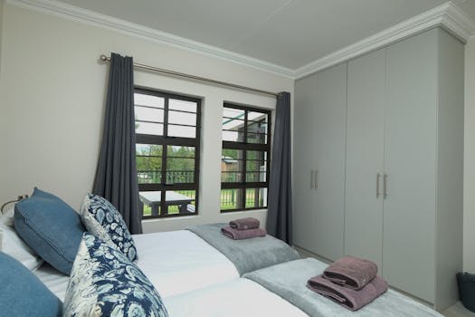Contemporary bedroom with neatly arranged bedding and a view of the garden.