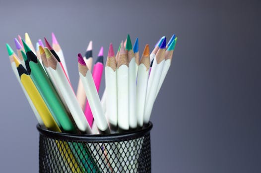 Vibrant colored pencils arranged in a black metal holder against a gradient background.