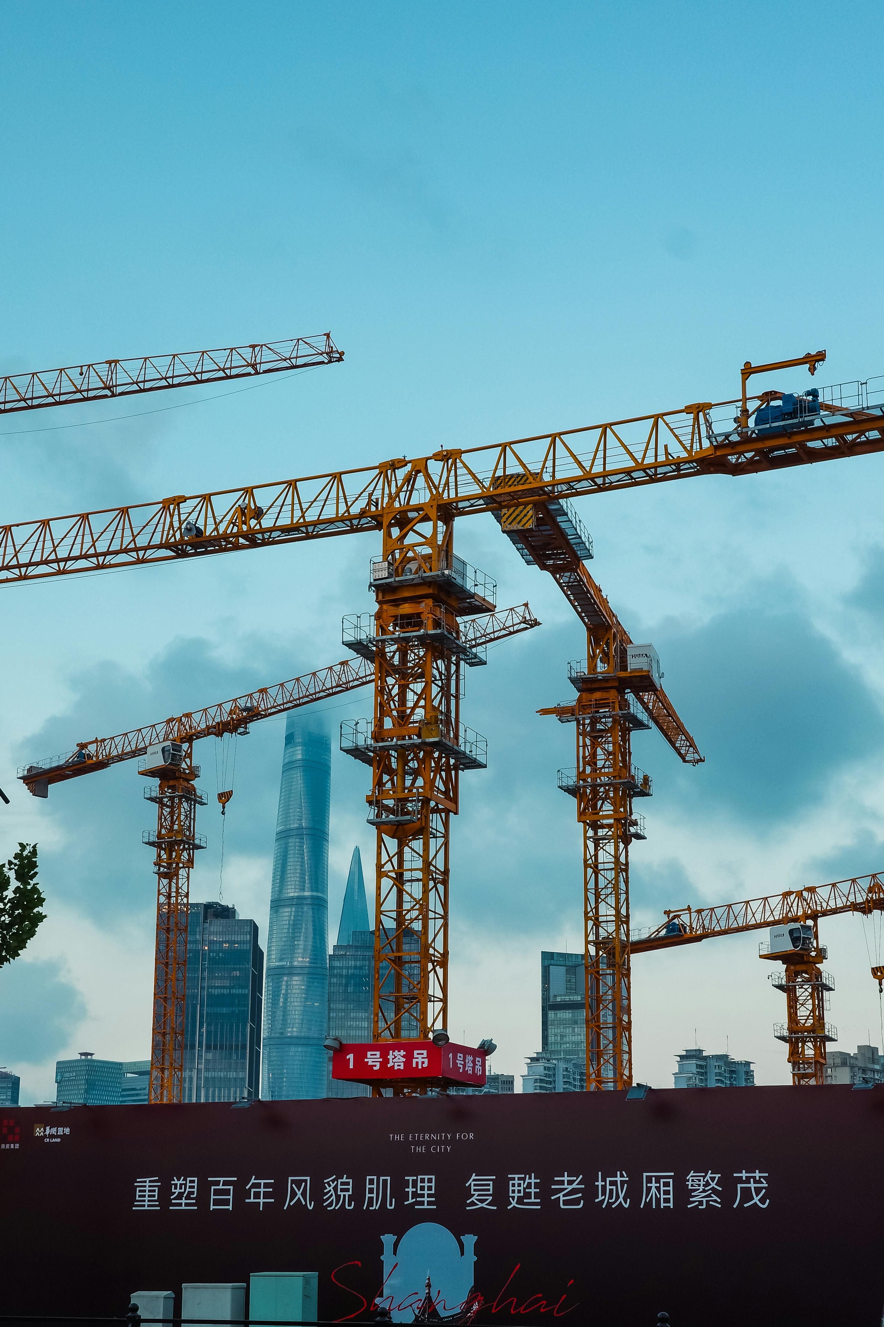 Shanghai skyline featuring cranes and the iconic Shanghai Tower.