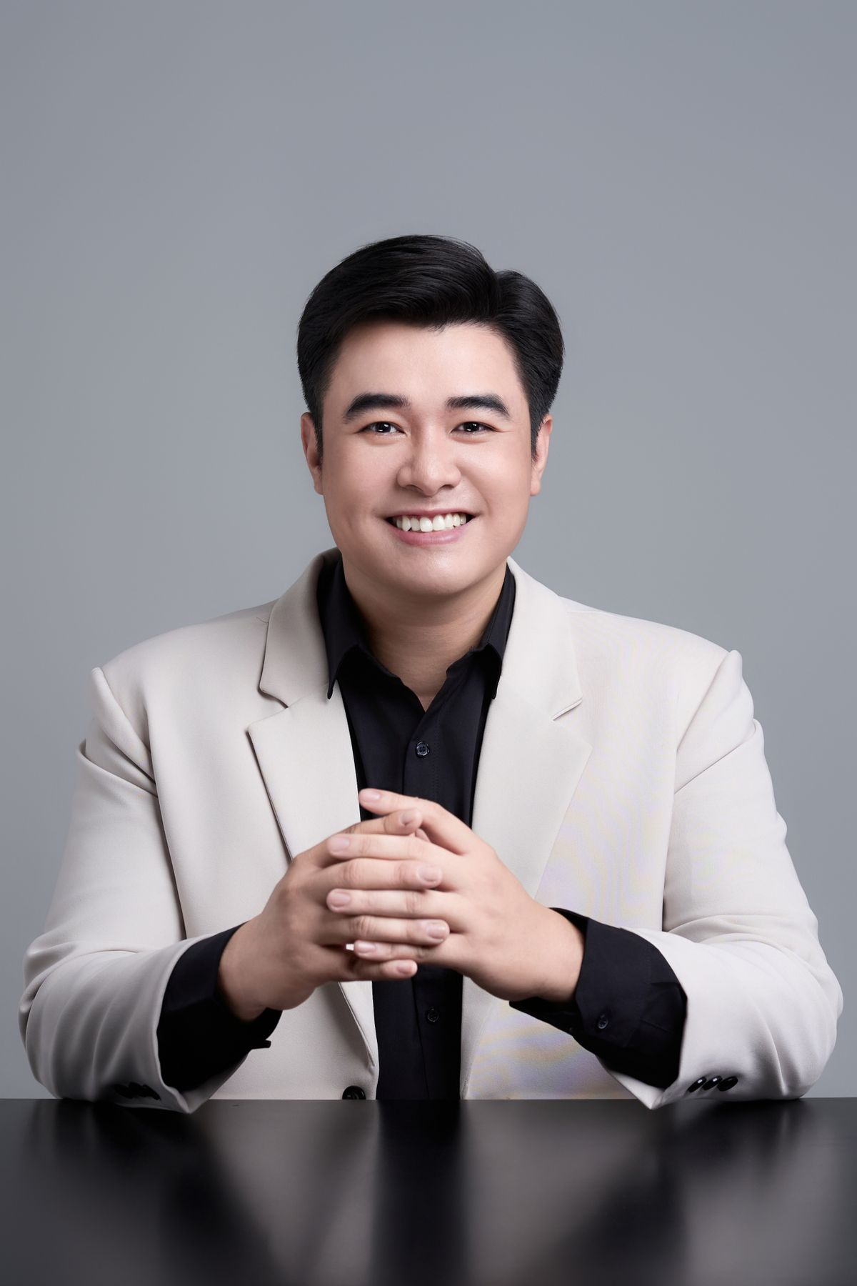 Professional portrait of an Asian man with a confident, warm smile in a studio setting