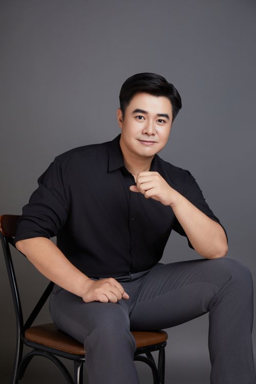 Free Portrait of a confident Asian man sitting in a studio setting, displaying a professional demeanor. Stock Photo