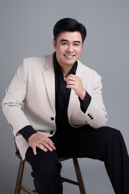 Free Confident man in beige blazer posing on stool against a gray background. Stock Photo