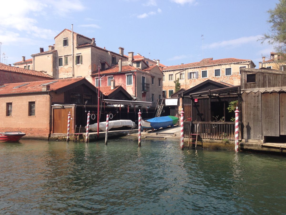 A picturesque view of a traditional boatyard along a Venetian canal under clear skies.