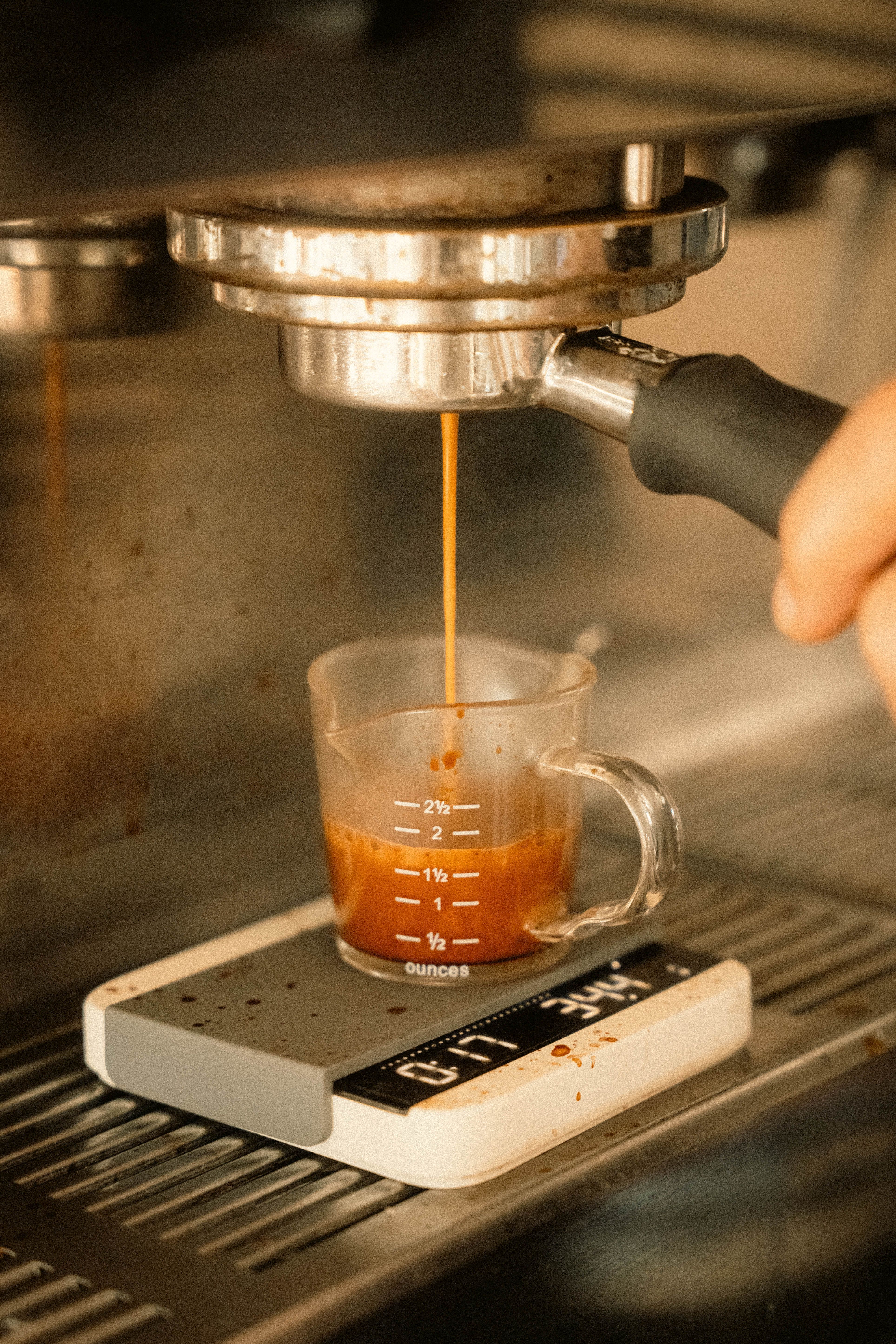 Espresso pouring into a measuring cup on a precision scale — professional baristas measure espresso yield by weight rather than volume to hit a consistent brew ratio every shot