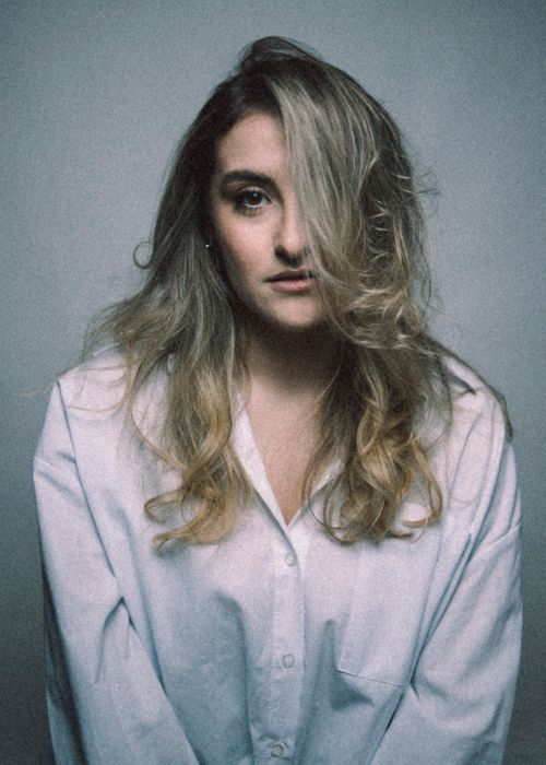 Free Artistic portrait capturing a woman with loose hair in a white shirt. Stock Photo
