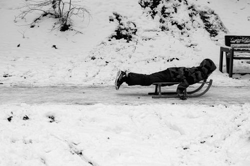 Free Monochrome image of a child enjoying sledding on a snowy day in Pristina. Stock Photo