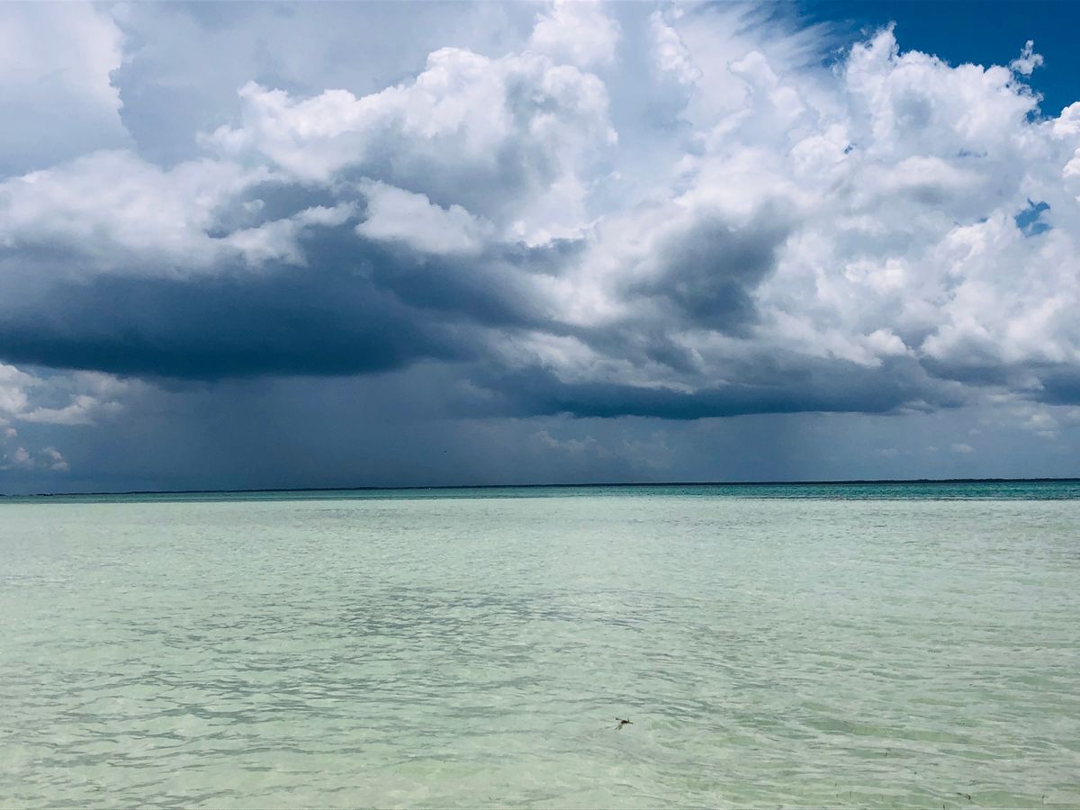 Nubes de tormenta dramáticas se juntan sobre el mar Caribe turquesa cerca de una isla.