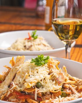 Close-up of a flavorful Italian pasta dish garnished with parmesan, paired with a glass of white wine.