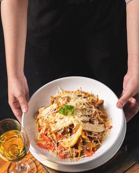 A plate of flavorful pasta topped with parmesan and parsley, served with white wine.