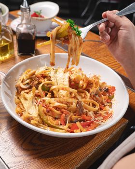 A tempting plate of Italian pasta with vegetables and parmesan served on a rustic wooden table.